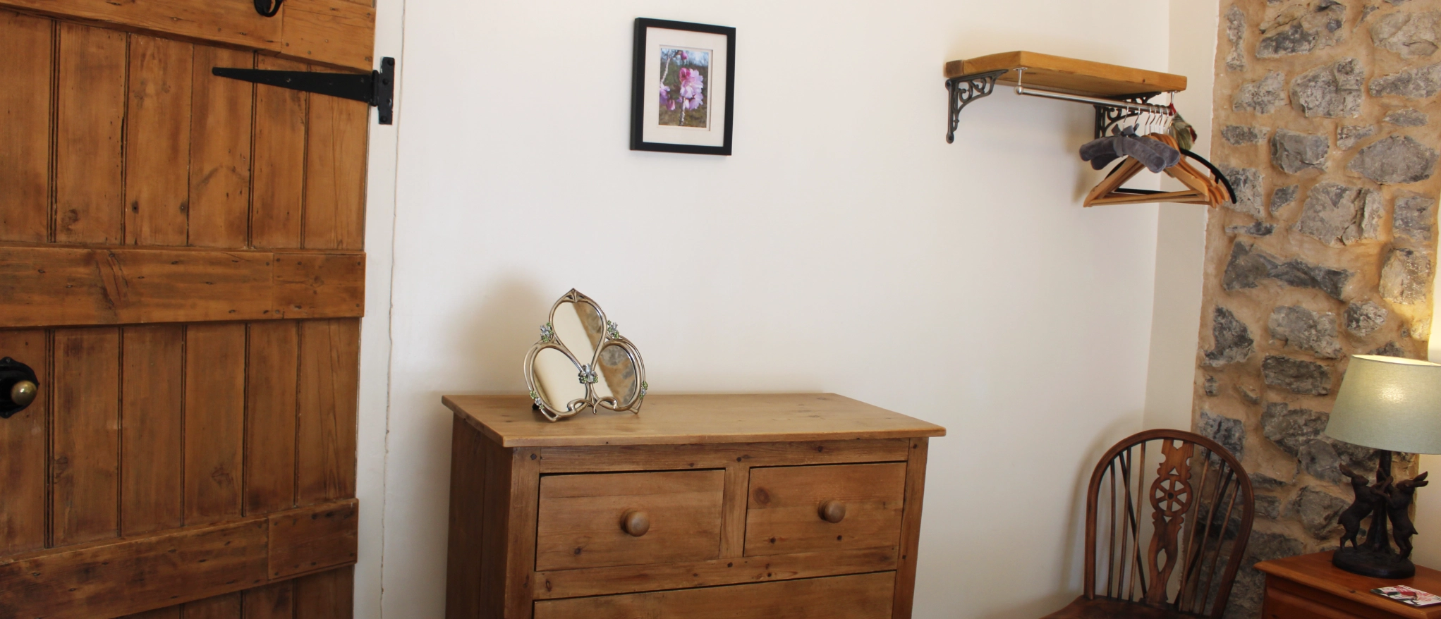 Bedroom storage and exposed stone wall at Kibble Cottage