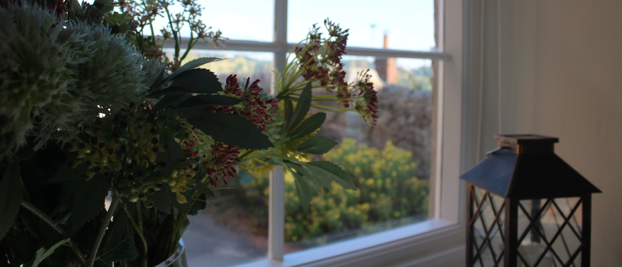 Flowers and lantern beside the window at Kibble Cottage